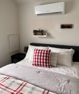 Example of a resident room including a nicely made bed and an overhead AC unit 